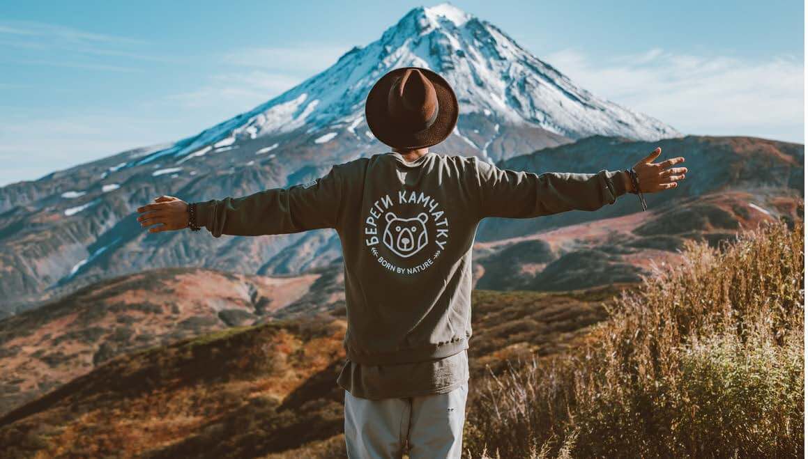 Man Standing In Front of Mountain With Arms Out