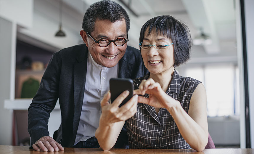 Cheerful Chinese couple using smartphone